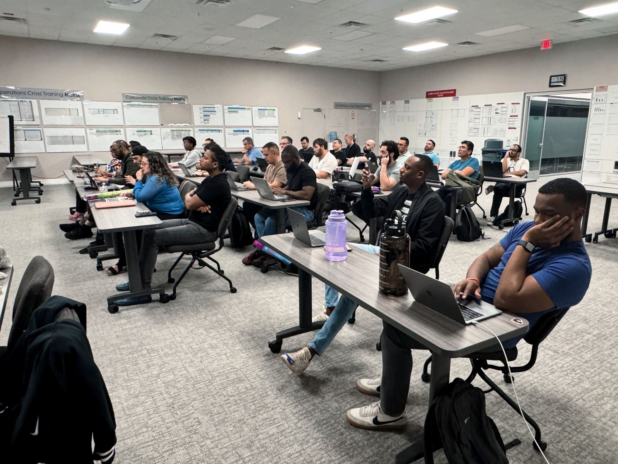 Lines of tables with 40 developers with laptops open watching presenter not pictured