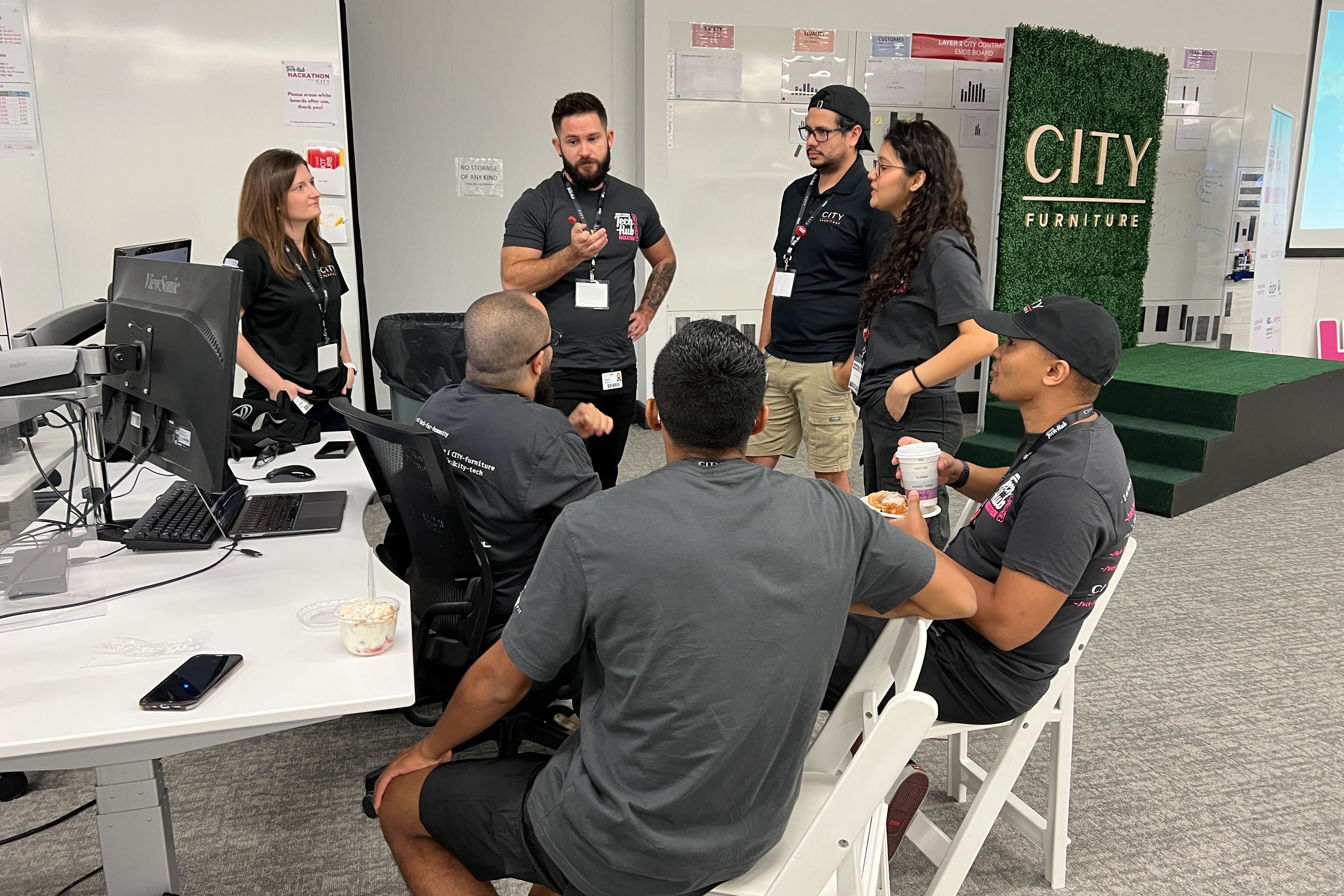 Group of seven engineers talking in a circle discussing a project