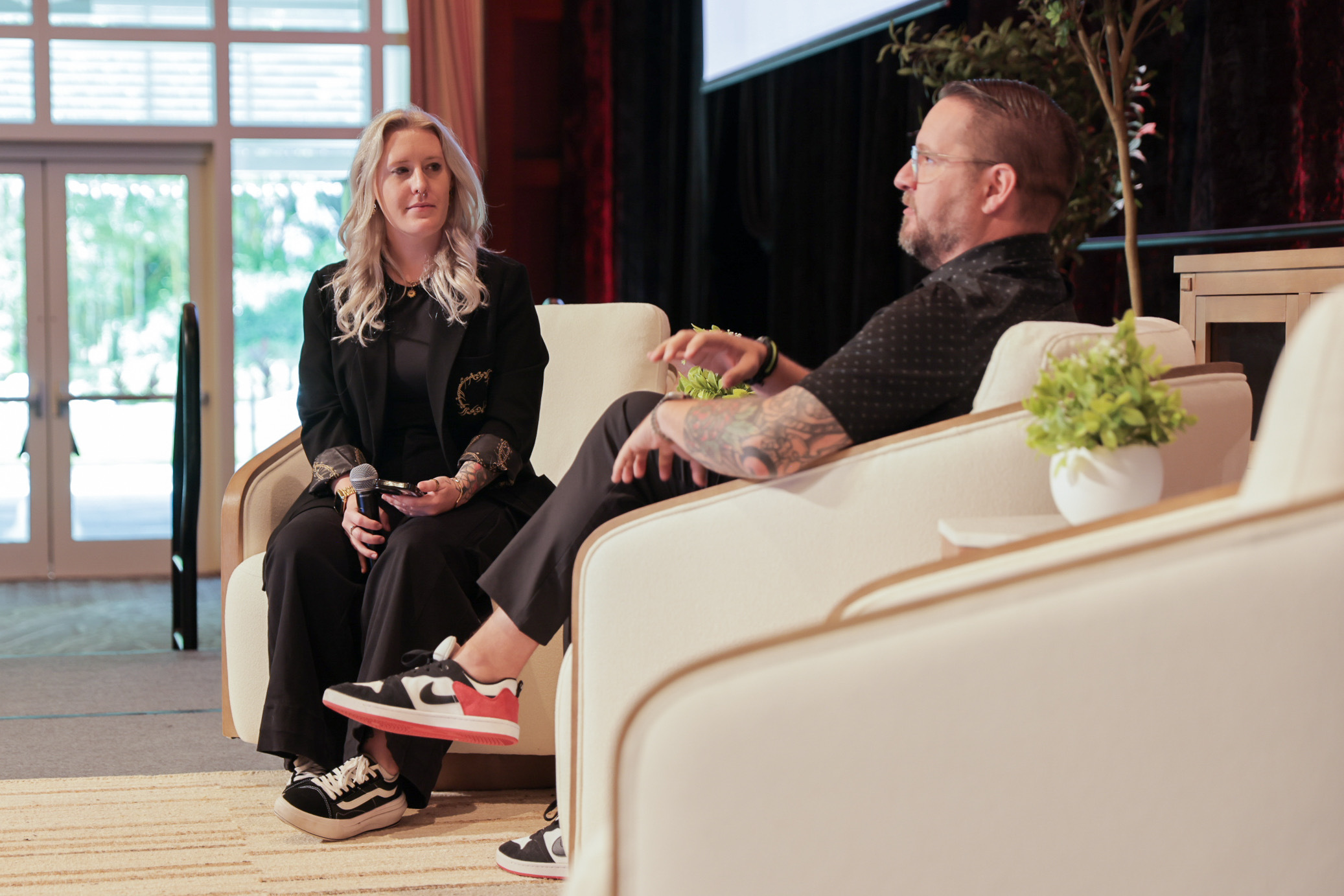 Rebecca interviewing man on stage camera is focused on her face smiling